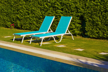 blue swimming pool in a resort with lounge chair