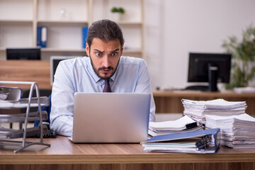 Obraz premium Young businessman employee unhappy with excessive work in the of