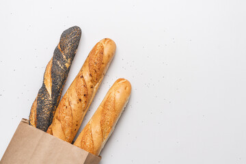 Fresh baguettes in paper bag on white background. Long bread. Fresh traditional French bakery