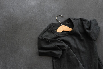 Gray T-shirt on wooden hanger. Black background, top view. Clothing sale concept