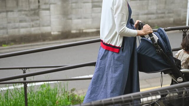 スロープをベビーカーを押して歩くお母さん