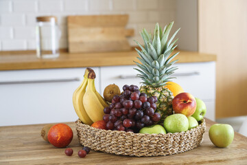 Fruit basket on the background of modern kitchen. Pineapple, grapes, peach, apple, orange, banana. Healthy food on wooden table