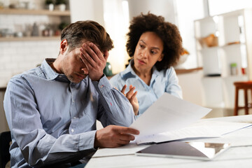 Fototapeta premium Young couple preparing bills to pay. Stressed woman and man having financial problems...