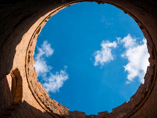 Inside the ruined and abandoned brick tower. View of the blue sky from the dilapidated building. Circular panorama
