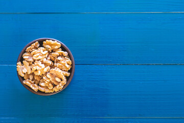 Flat lay view of hazelnut bowl over trendy blue background with copy space