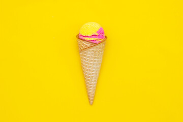 Sweet yellow pink fruit ice-cream sorbet in a waffle cone with banana and strawberry flavor isolated on a bright color yellow background. Copy space for text or design. Summer concept