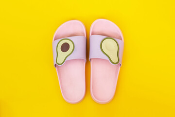 Trendy light pink and purple female beach rubber flip-flops with avocado halves isolated on a...