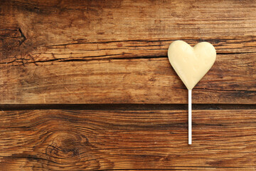 Chocolate heart shaped lollipop on wooden table, top view. Space for text