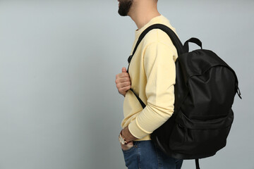 Fototapeta Young man with stylish backpack on light grey background, closeup. Space for text obraz