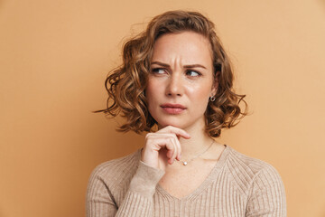 Young ginger puzzled woman frowning and looking aside
