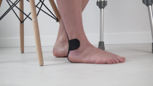 Close-up of the woman's leg in the teip on the floor, developing ankle elasticity, rehabilitation after injury.