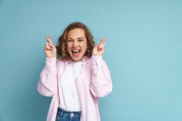 Young ginger woman laughing while holding fingers crossed for good luck