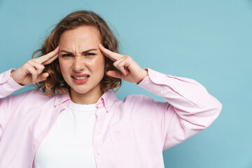 Young ginger woman with headache frowning while rubbing her temples