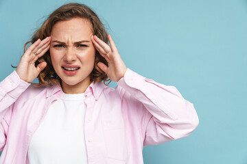 Young ginger woman with headache frowning while rubbing her temples