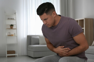 Man suffering from stomach ache at home, space for text. Food poisoning