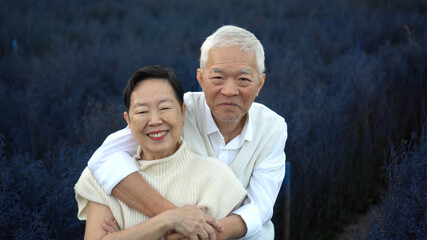 Asian senior couple hugging dating anniversary at purple flower field together