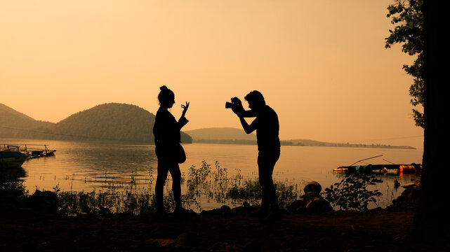 Silhouette of a cheerful couple clicking pictures from camera