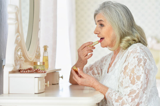 portrait of happy senior woman applying makeup