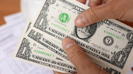 Family budgeting. Man counting american dollar bills close-up