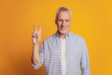 Naklejka premium Trendy old man showing v-sign isolated yellow background