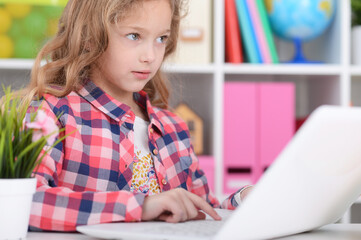 Cute little girl using modern laptop