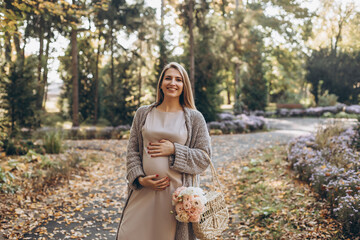 A pregnant woman walks through the autumn forest. Yellow leaves around?