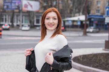 Portrait of a beautiful and positive redhead woman with clothes in grunge style. Posing while walking