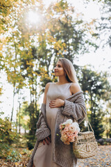 Pregnant beautiful woman walks in the autumn garden. She breathes the clean forest air, which is good for her health.