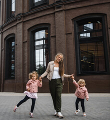 young beautiful mother with long hair with children on walk in street happiness joy fun motherhood
