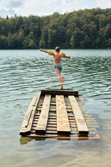 Fototapeta na wymiar child is jumping from a wooden pier in a lake