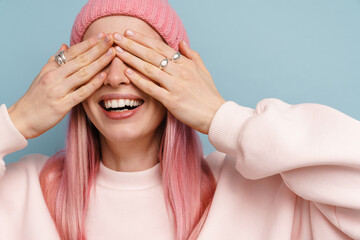Young white woman with pink hair smiling and covering eyes with hands