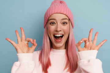 Young white woman with pink hair laughing and showing okay sign