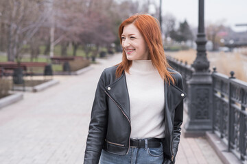 Portrait of a beautiful and positive redhead woman with clothes in grunge style. Posing while walking