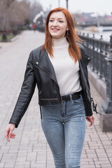Fototapeta premium Portrait of a beautiful and positive redhead woman with clothes in grunge style. Posing while walking