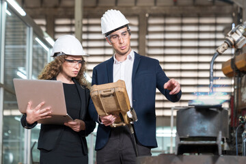 Engineers and technicians are using a remote control and a laptop to control the machine.