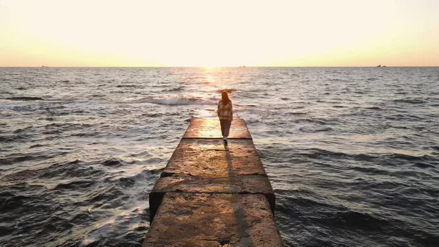 Slow motion shot of young woman walking on stone pier
