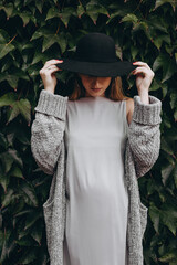 Serious pregnant girl in a black hat.