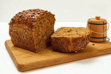 Cut loaf of bread on wooden cutting board on white background