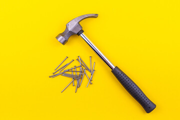 hammer and small nails lie on a yellow background