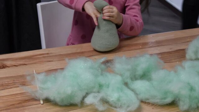 Toddler girl fingers stuffing soft sintepon inside handicraft felt toy. Green cotton sintepon hollow PP cotton filling material for making stuffed toys. Kids sensory activity for fine motor skills