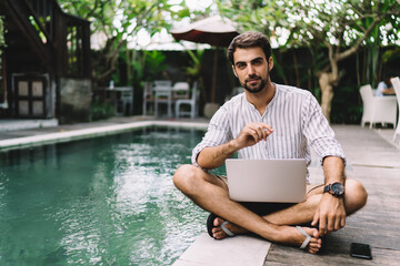 Young man with working on laptop while enjoying summer holiday