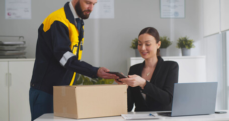 Young businesswoman receiving parcel in office - obrazy, fototapety, plakaty