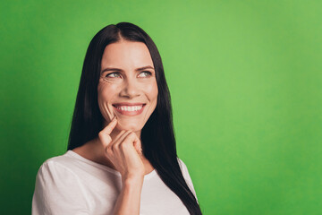 Fototapeta premium Young thoughtful girl touch chin hand dreaming on green background