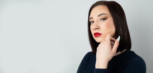Portrait of a young beautiful brunette with piercings in her nose. On an isolated background