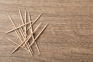 Disposable toothpicks on wooden background, flat lay. Space for text