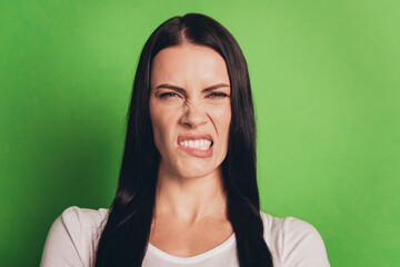 Portrait of unhappy caucasian woman expressing dislike standing over green background