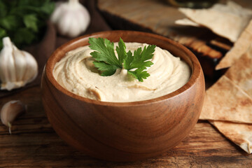 Delicious hummus and pita chips on wooden table, closeup