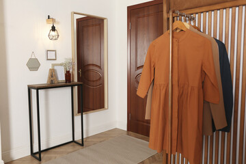 Modern hallway interior with stylish furniture and clothes rack