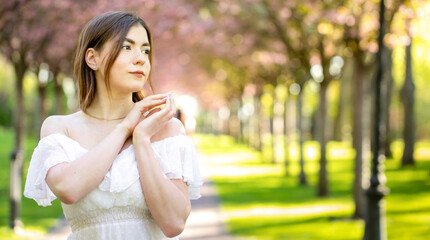 Dreamy young brunette in a bright summer park.