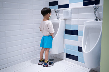 A boy is pissing himself in the bathroom.